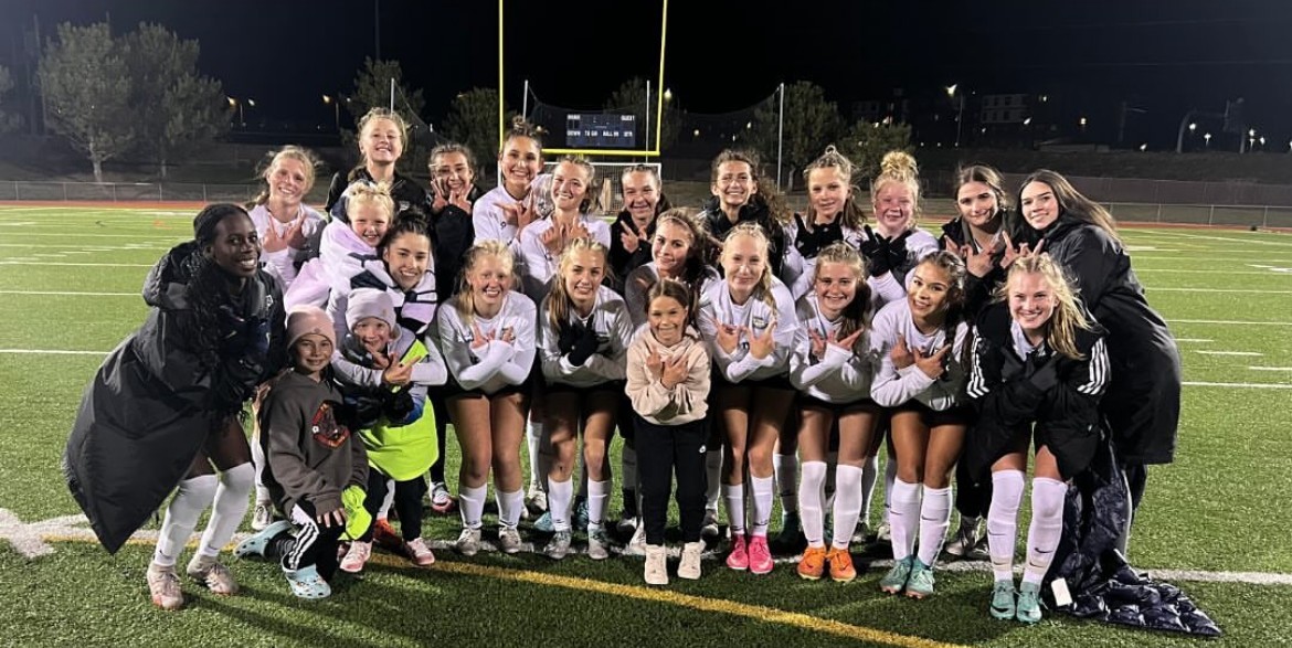 Girls soccer players posing for picture on field